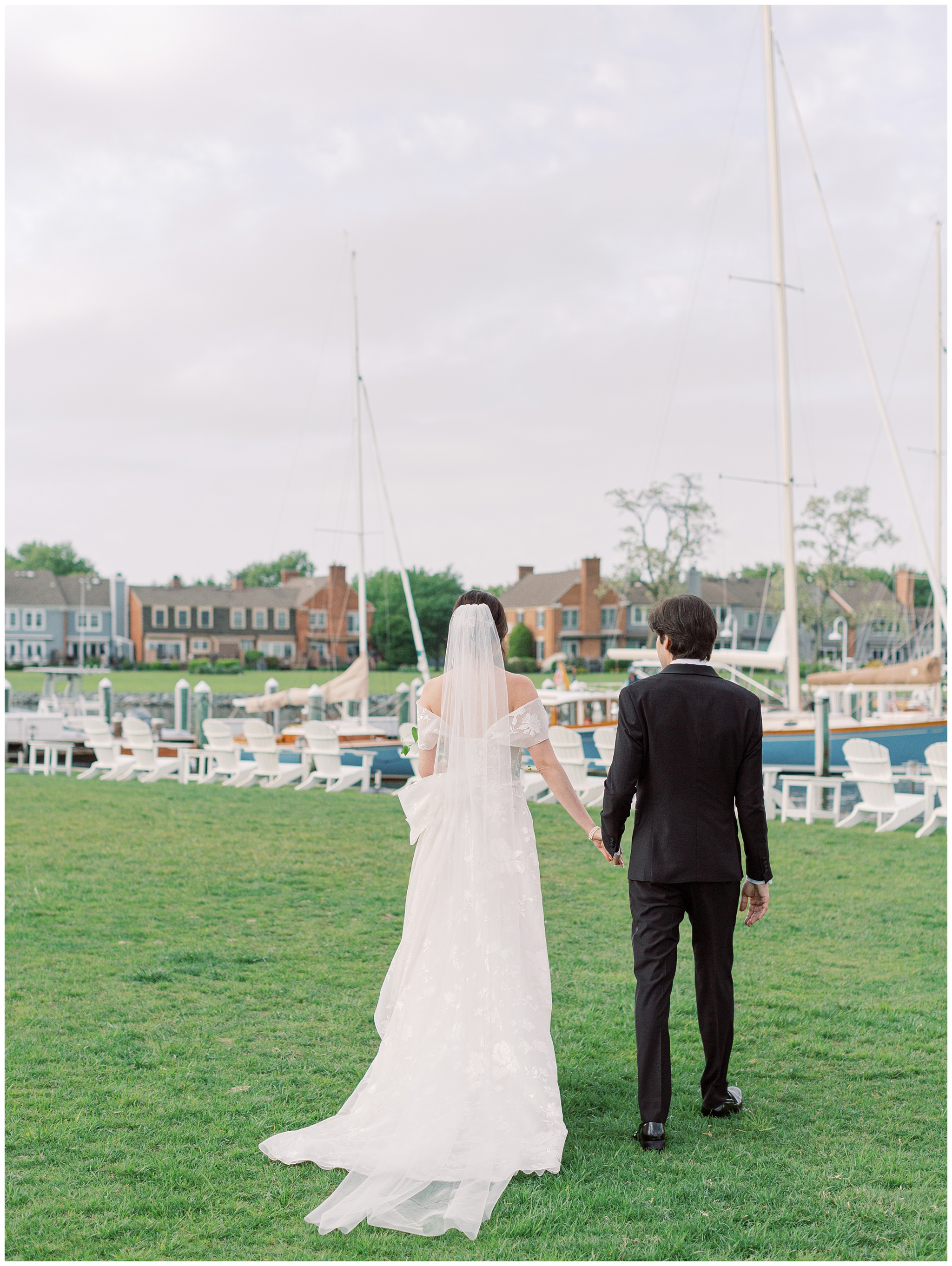 Bride and Groom walking away towards sailboats at the Inn at Perry Cabin