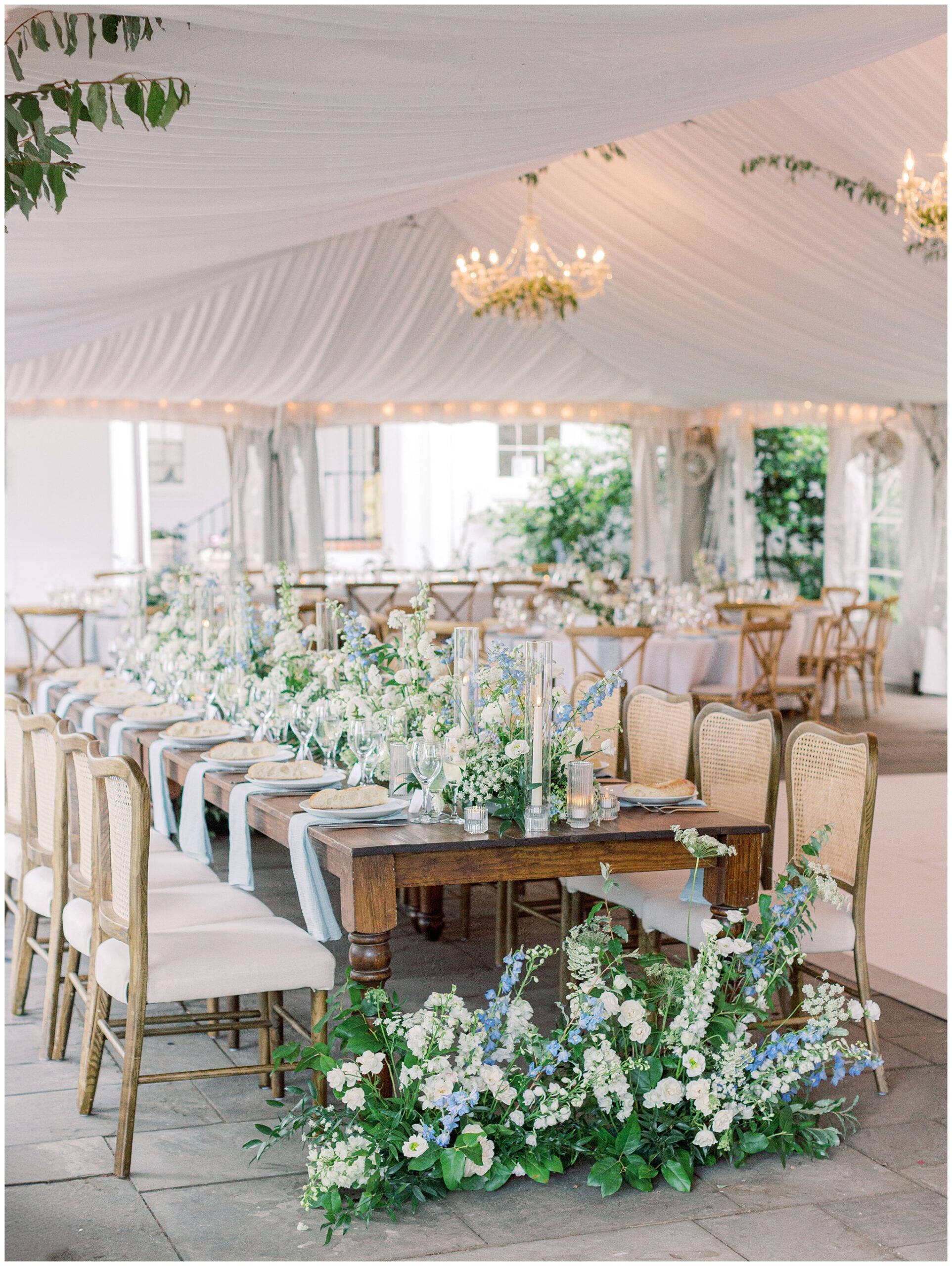 Elegant River Farm wedding reception tent featuring lush blue and white floral arrangements