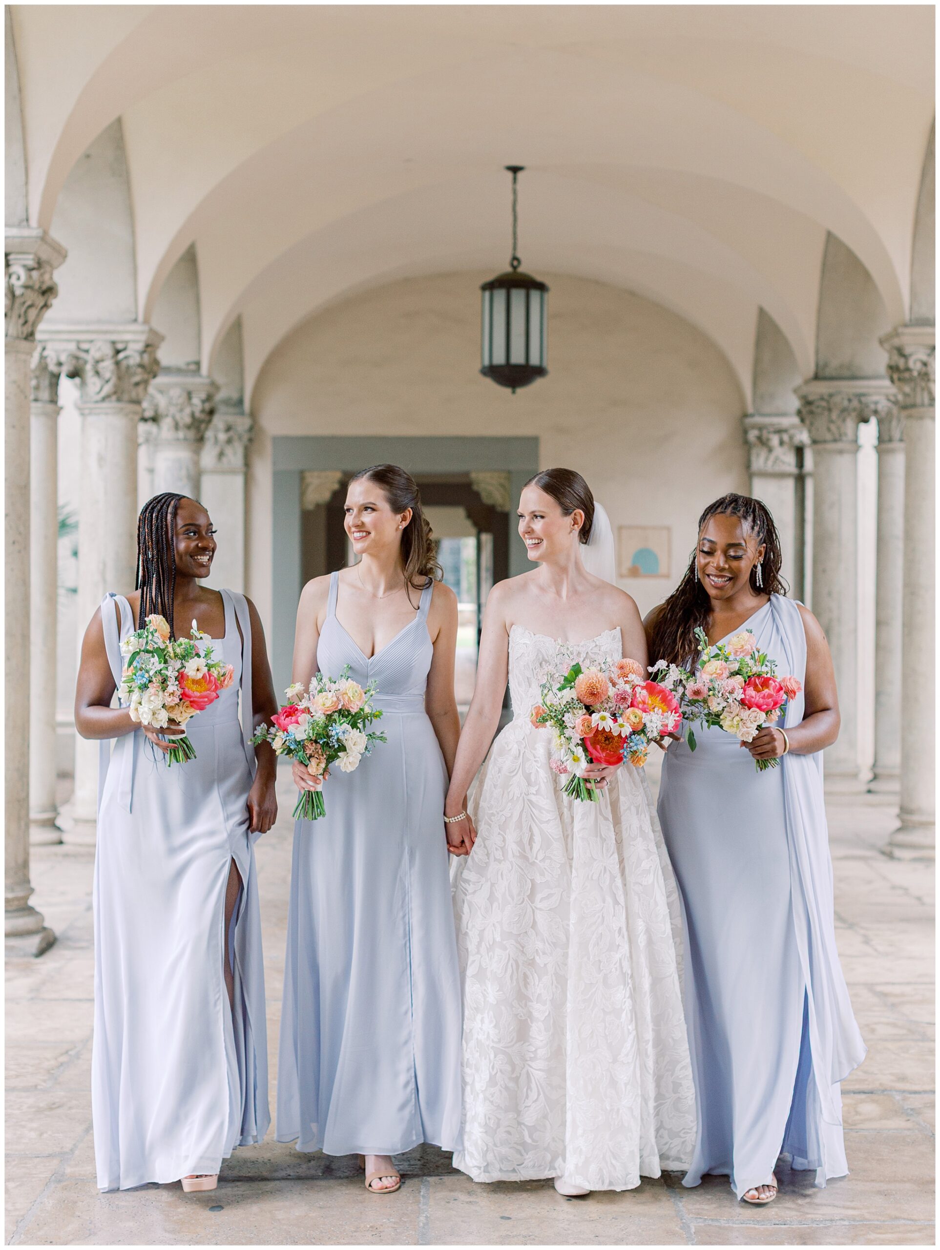 Bridesmaids walking under columns at Caltech Athenaeum wedding