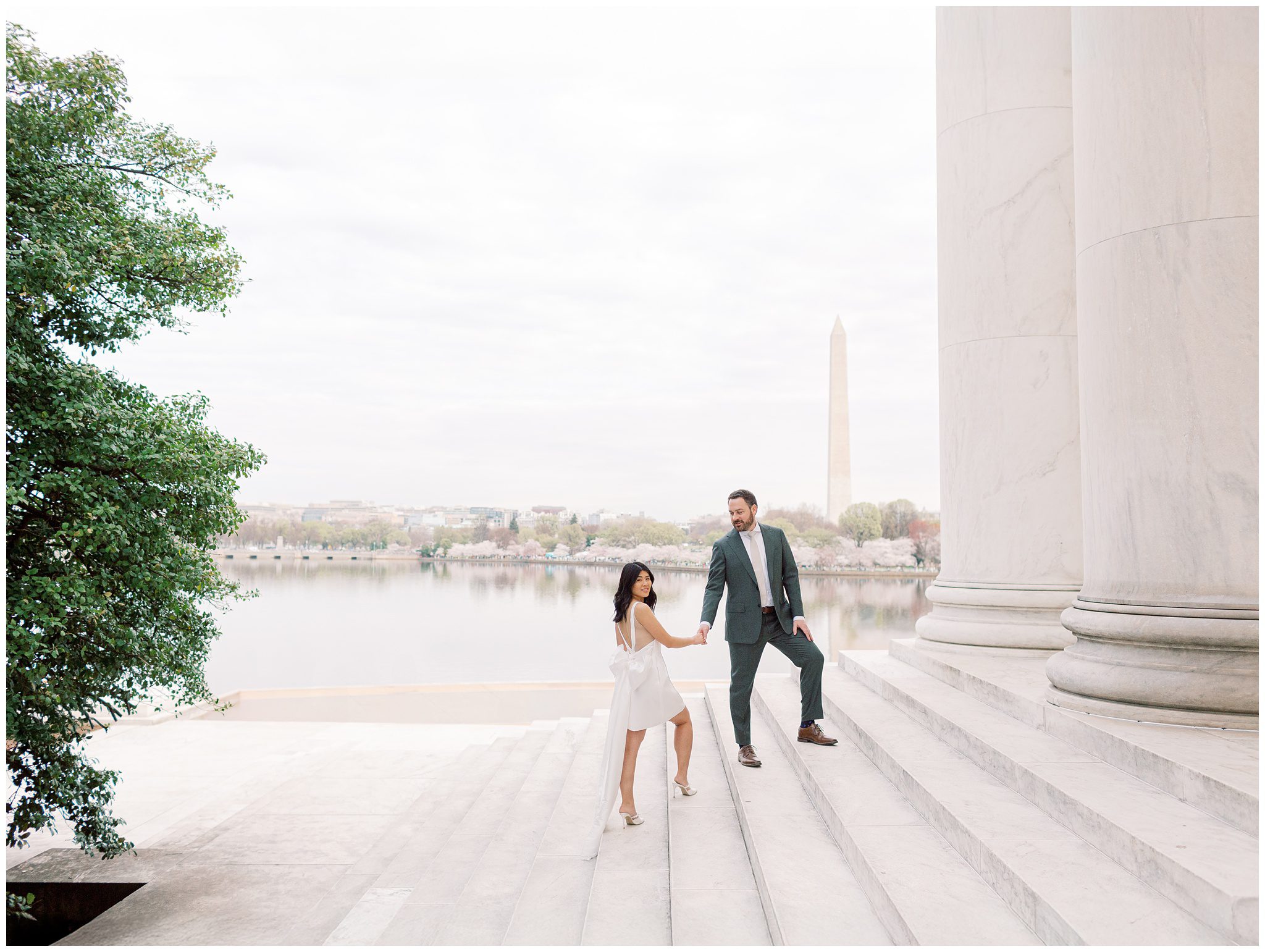 Bride wearing a Jenny Yoo dress with oversized bow during cherry blossom engagement session at the Jefferson Memorial