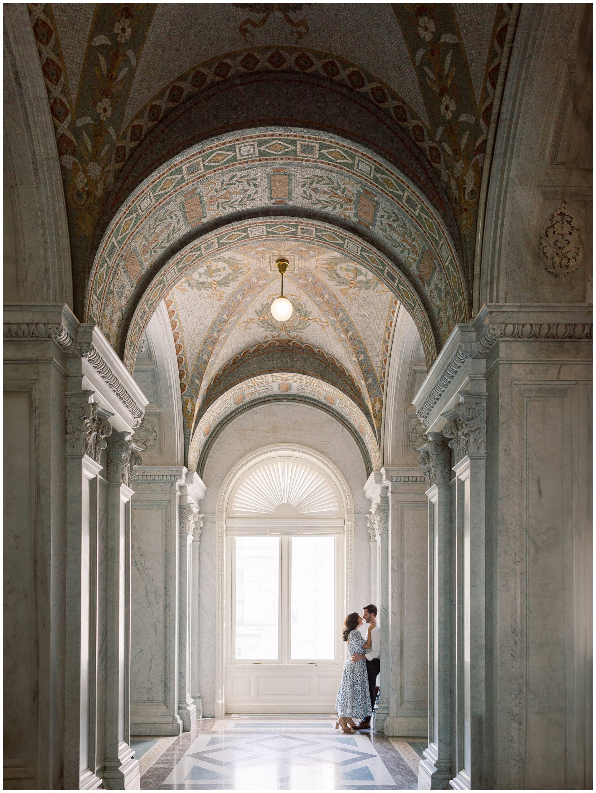 Couple sharing a romantic moment during their Library of Congress engagement session in Washington, DC, with marble walls and classic architecture in the background.