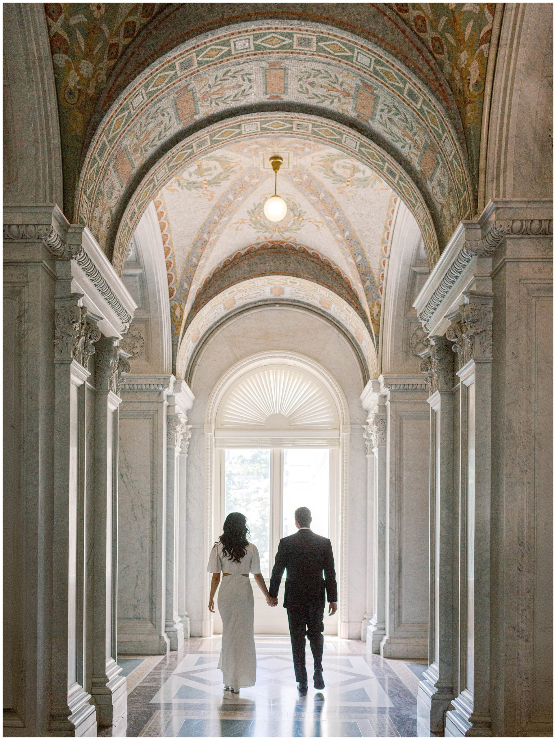 Couple walking away under elegant archway