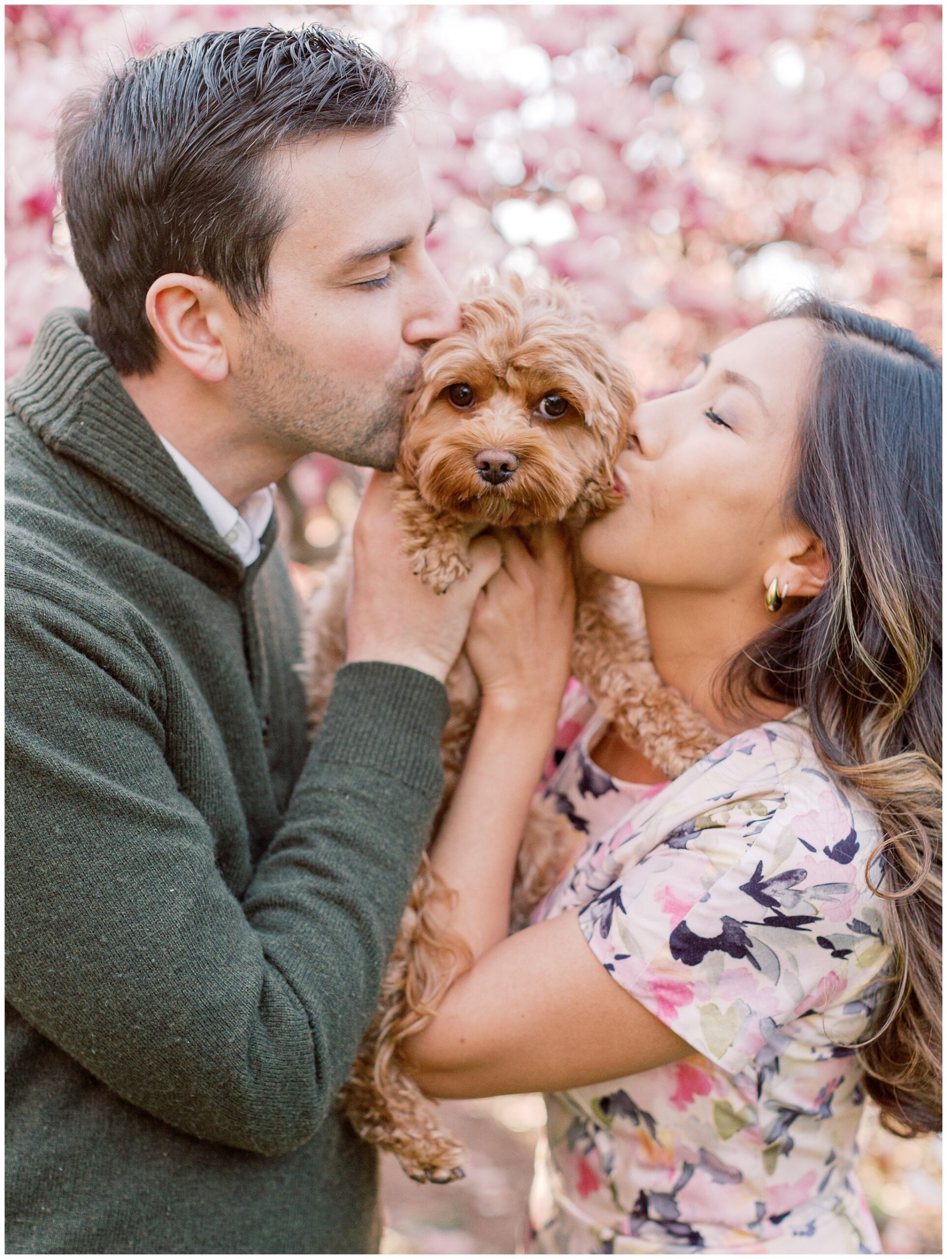 Lynette and Alex kissing their Cavapoo, Leo, in the magnolias