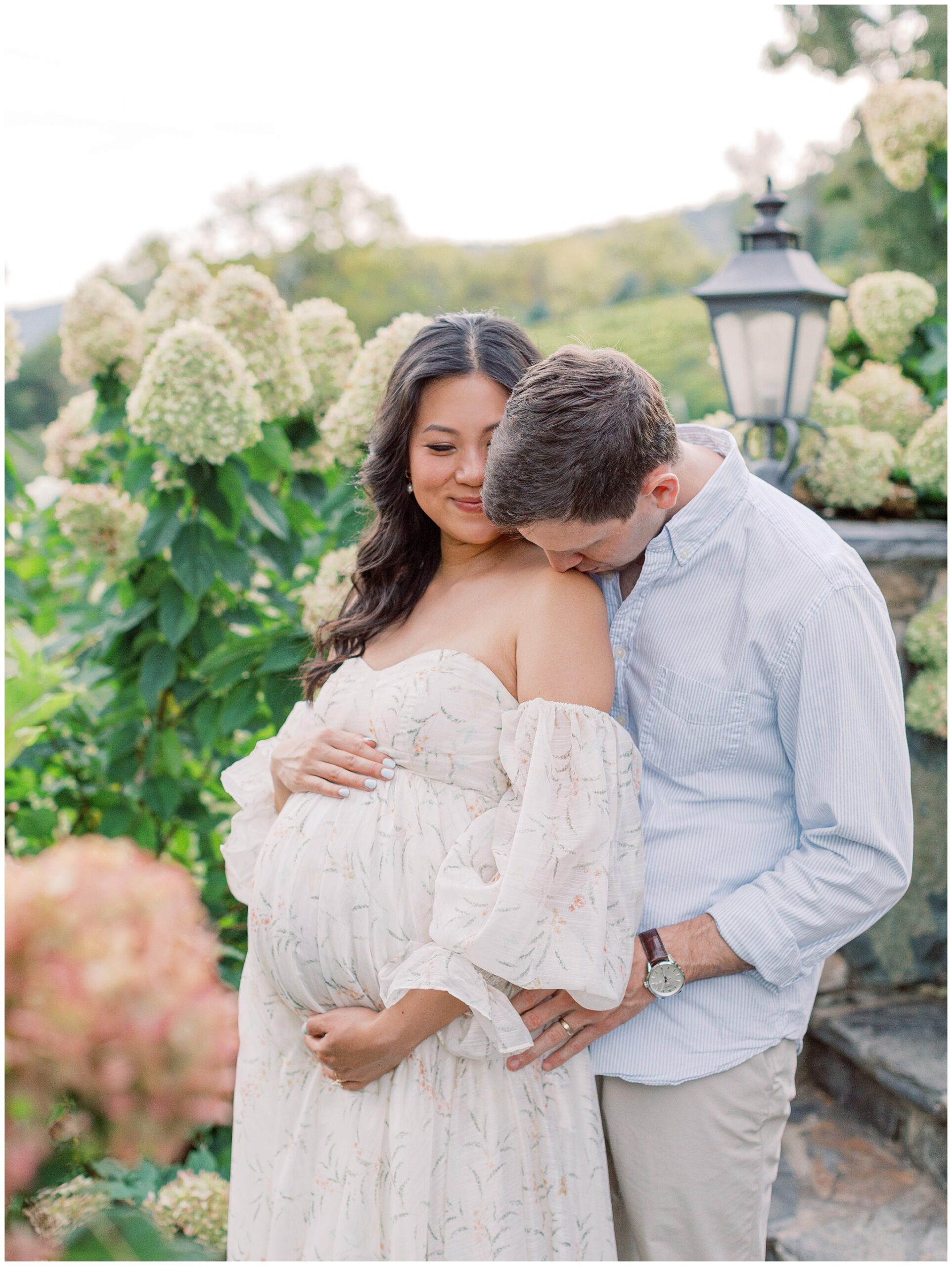 Couple embracing in the hydrangeas during maternity session at Bluemont Vineyard