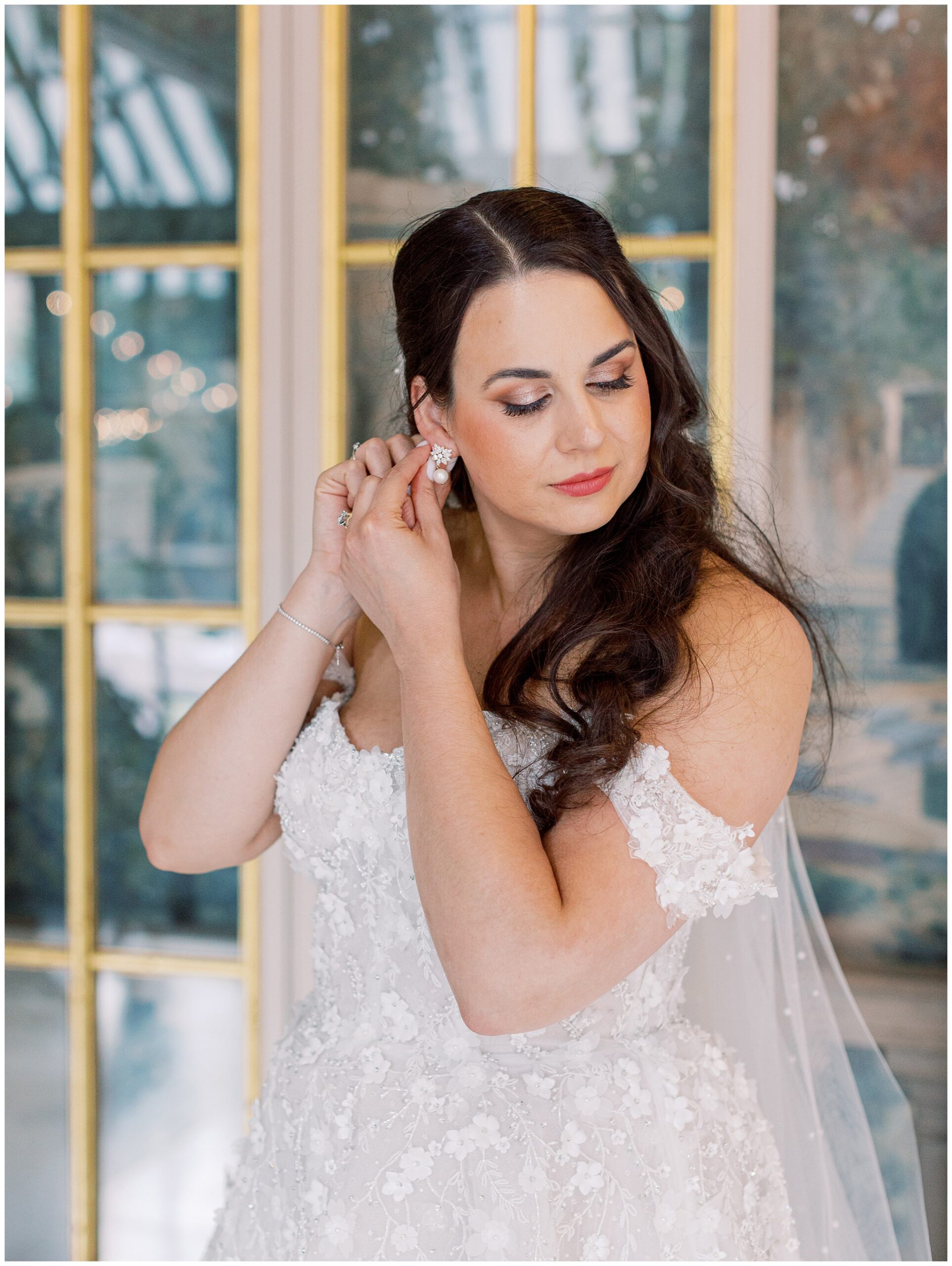 Bride putting on earrings in Larz Anderson House's Winter Room