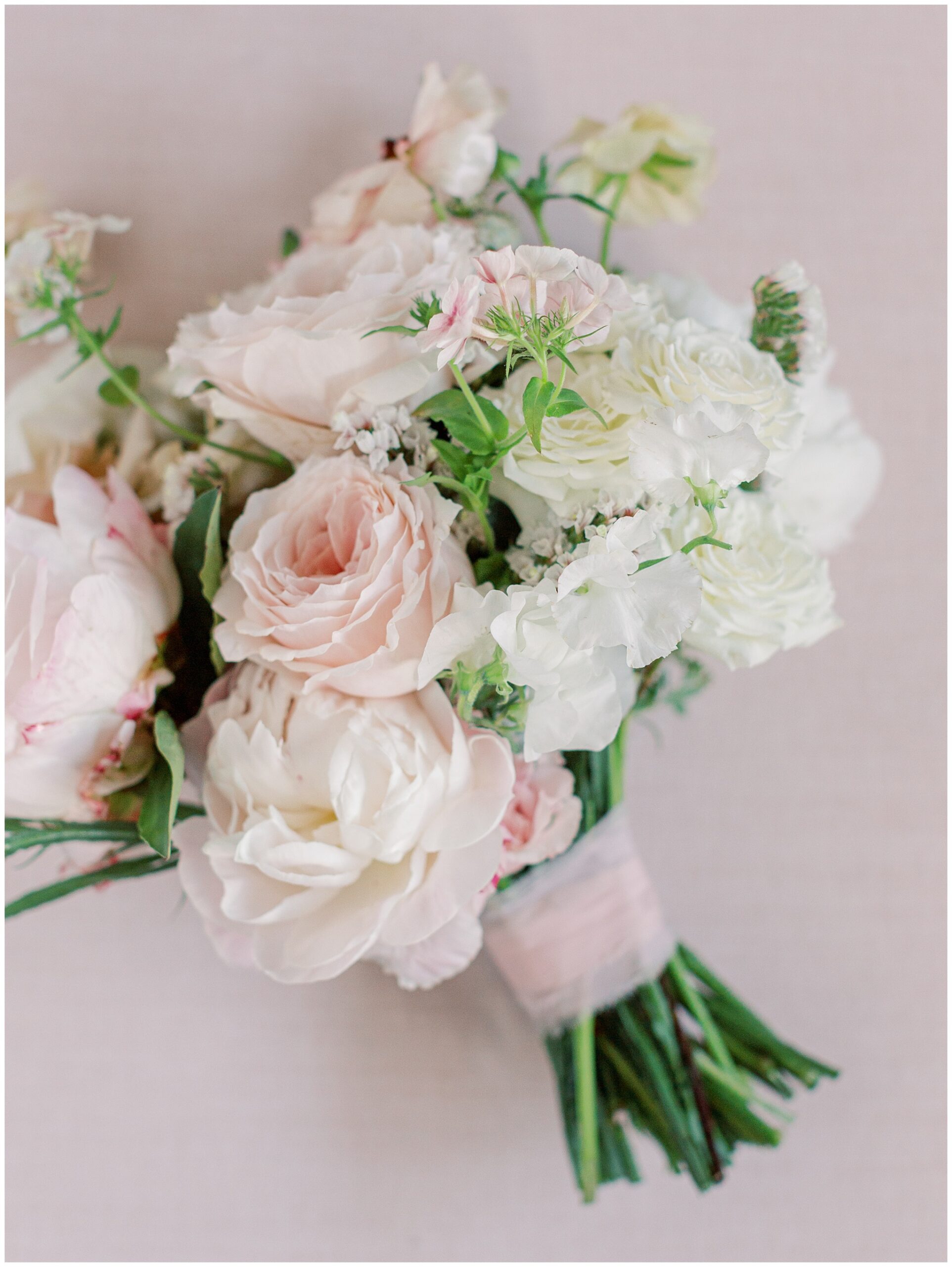 Close up of bridal bouquet in shades of pink, white, and ivory