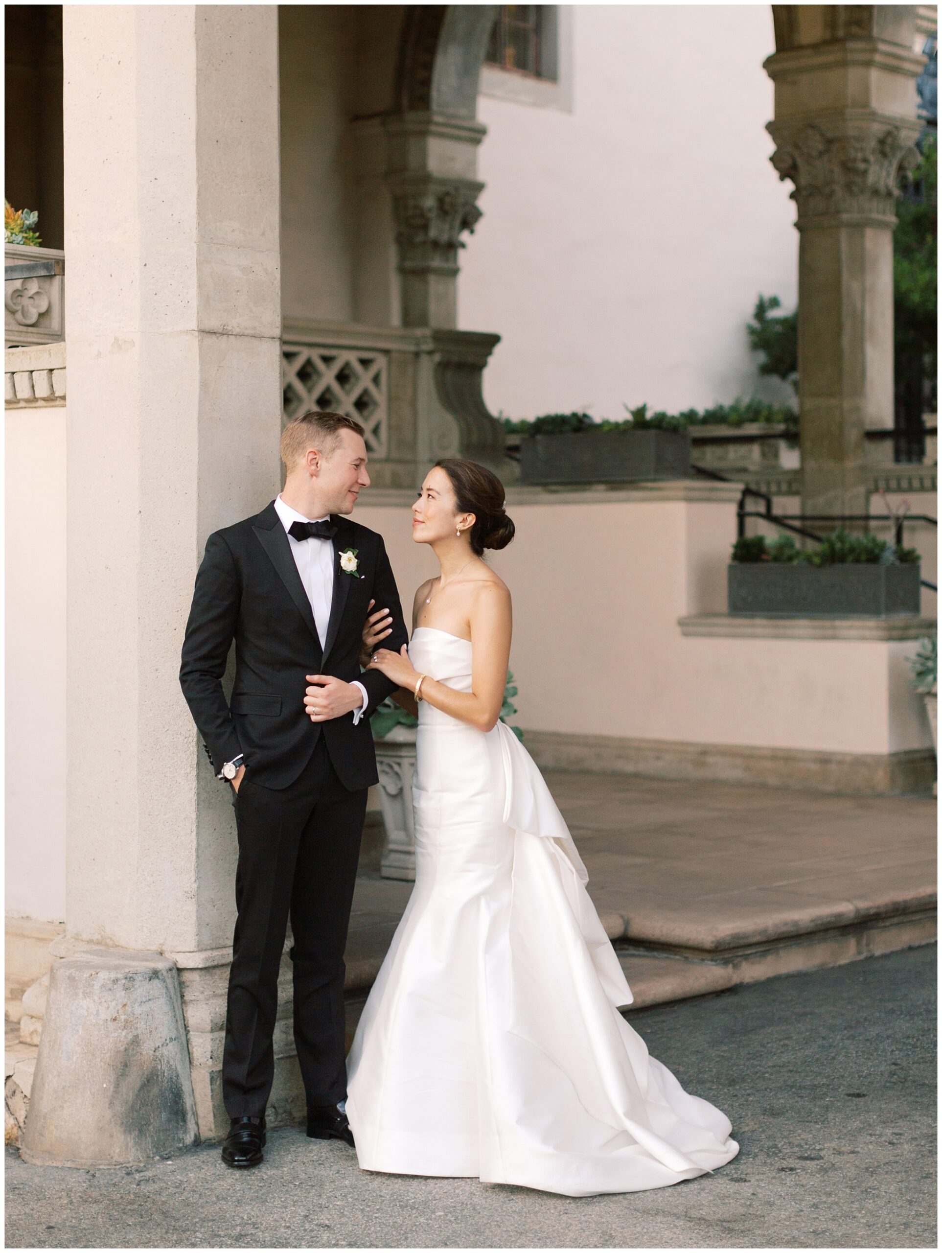 Bride and groom leaning against a pillar at the Athenaeum entrance during their wedding portraits