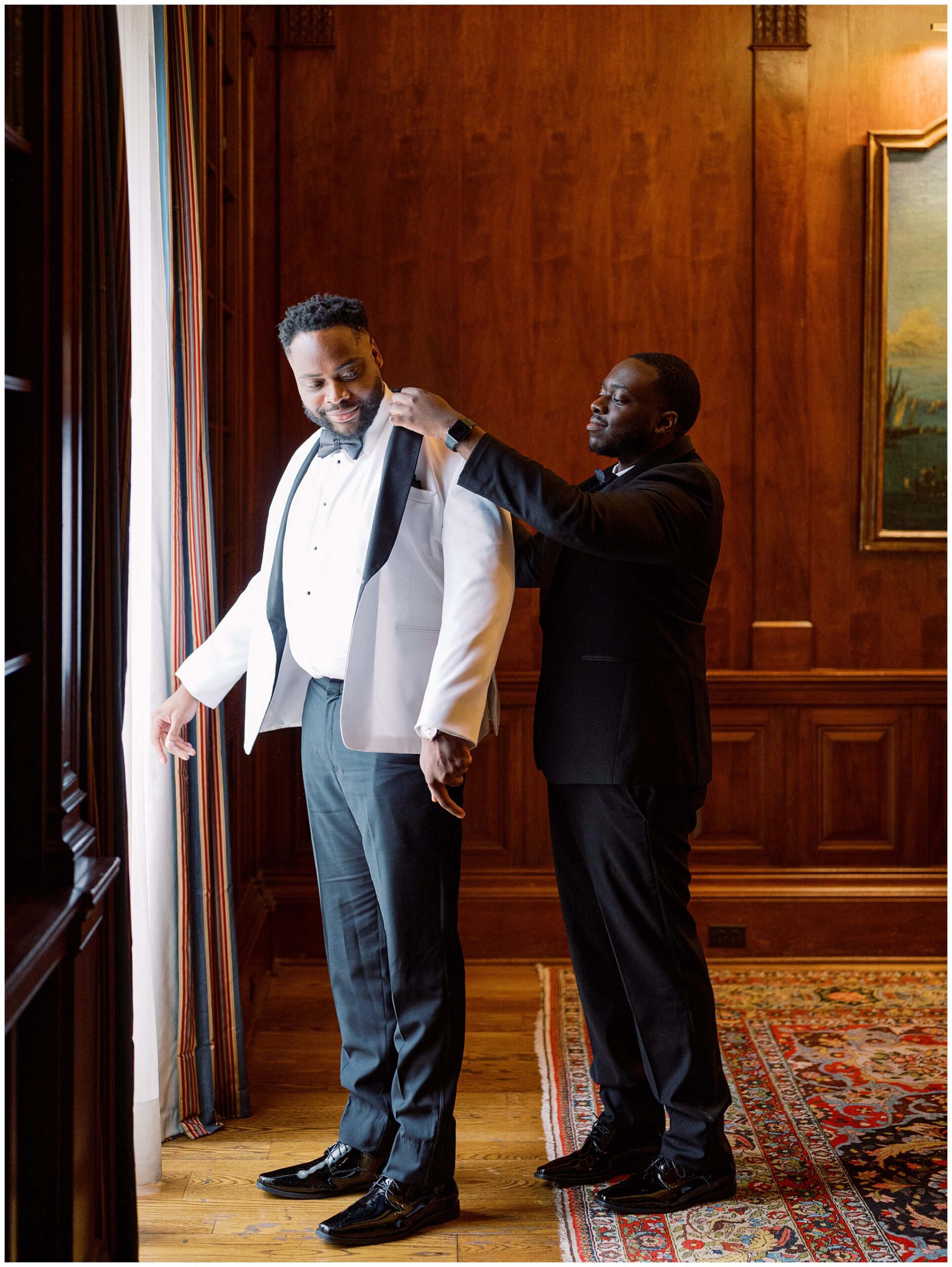 Groom getting ready with his brother by the window in the Library before his wedding ceremony