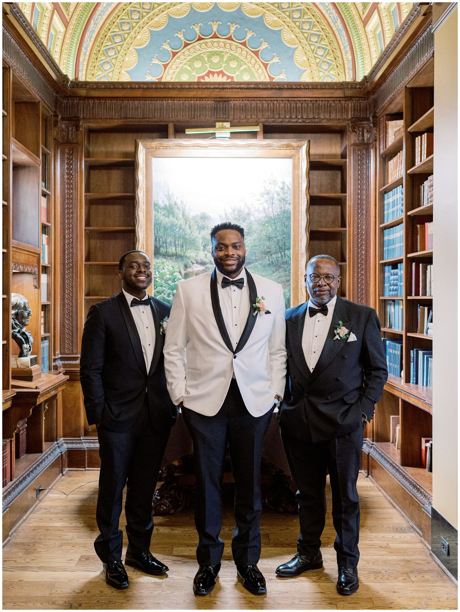 Groom standing with his father and brother in the Library during a quiet moment before the wedding ceremony