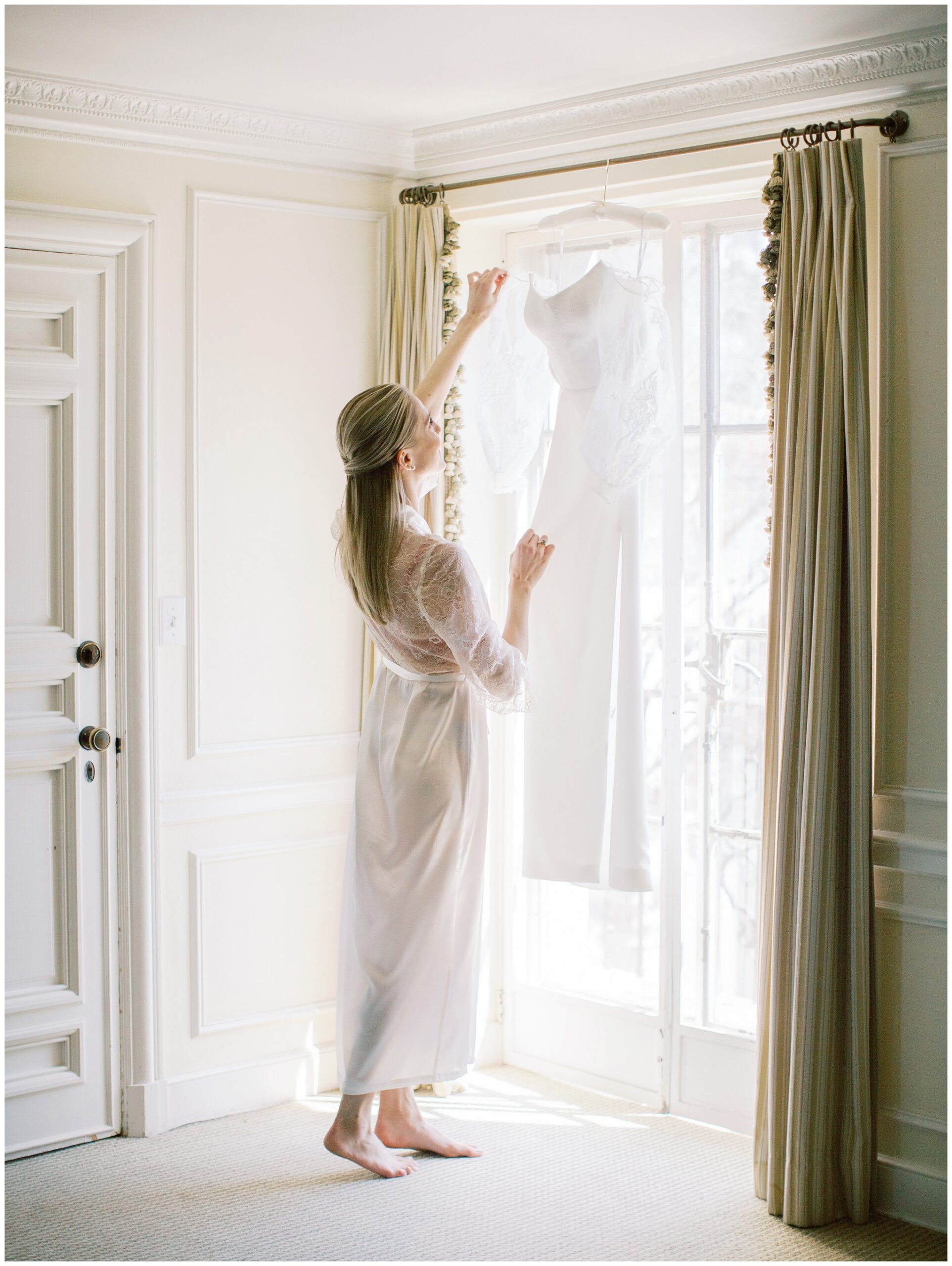 Bride reaching up on her tiptoes to retrieve her wedding dress in the Mezzanine bridal suite