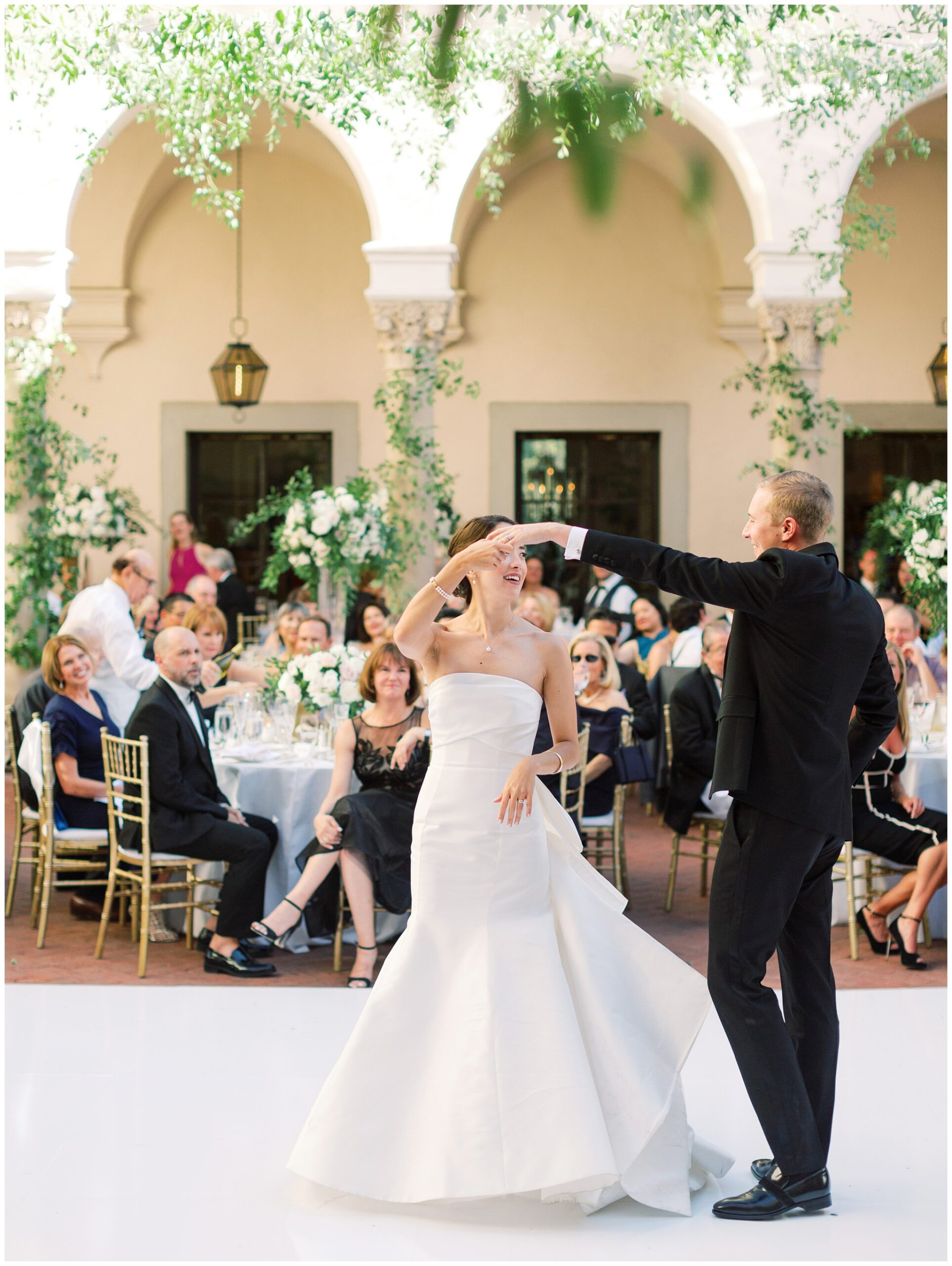 Bride and groom sharing their first dance beneath cascading greenery at the Caltech Athenaeum wedding reception