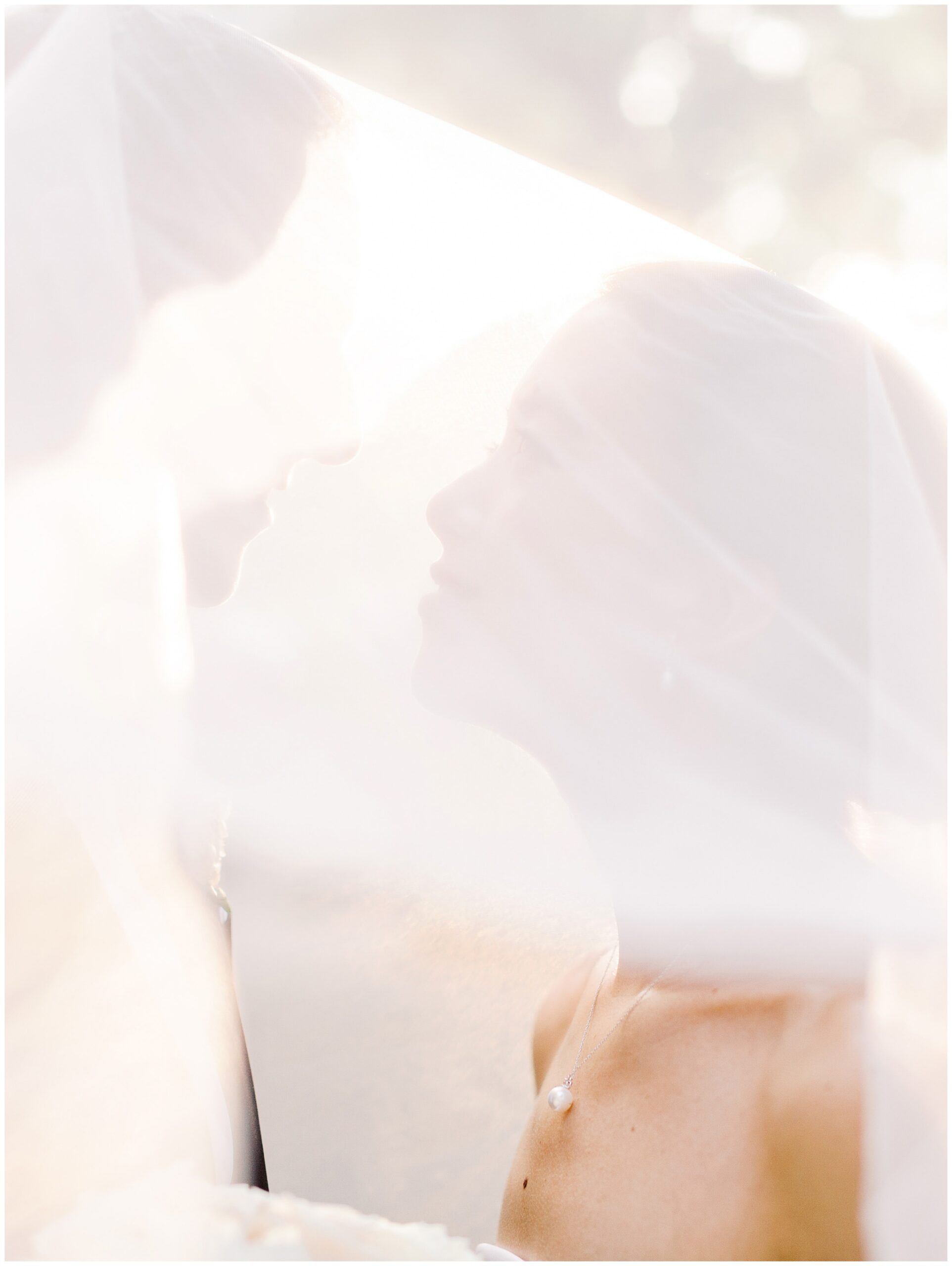 Bride and groom sharing a sunset portrait beneath the bride’s veil