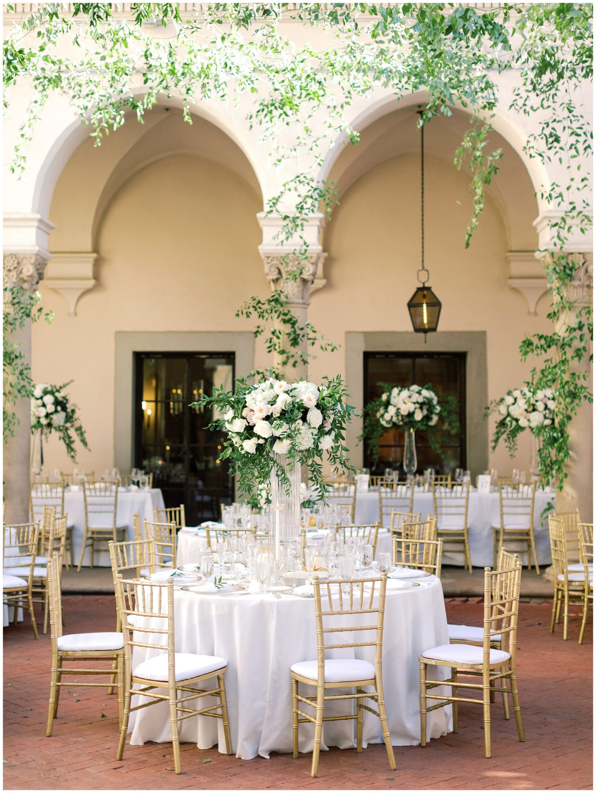Reception table on the West Patio at the Caltech Athenaeum with lush floral centerpieces, candles, and elegant place settings