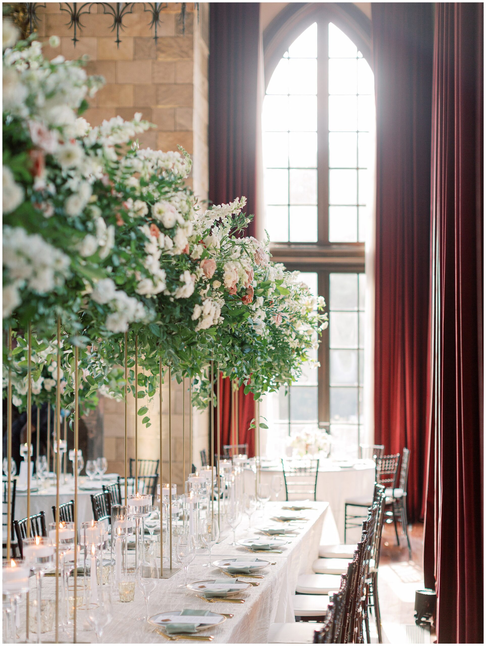Ballroom reception head table decorated with lush greenery and floral arrangements