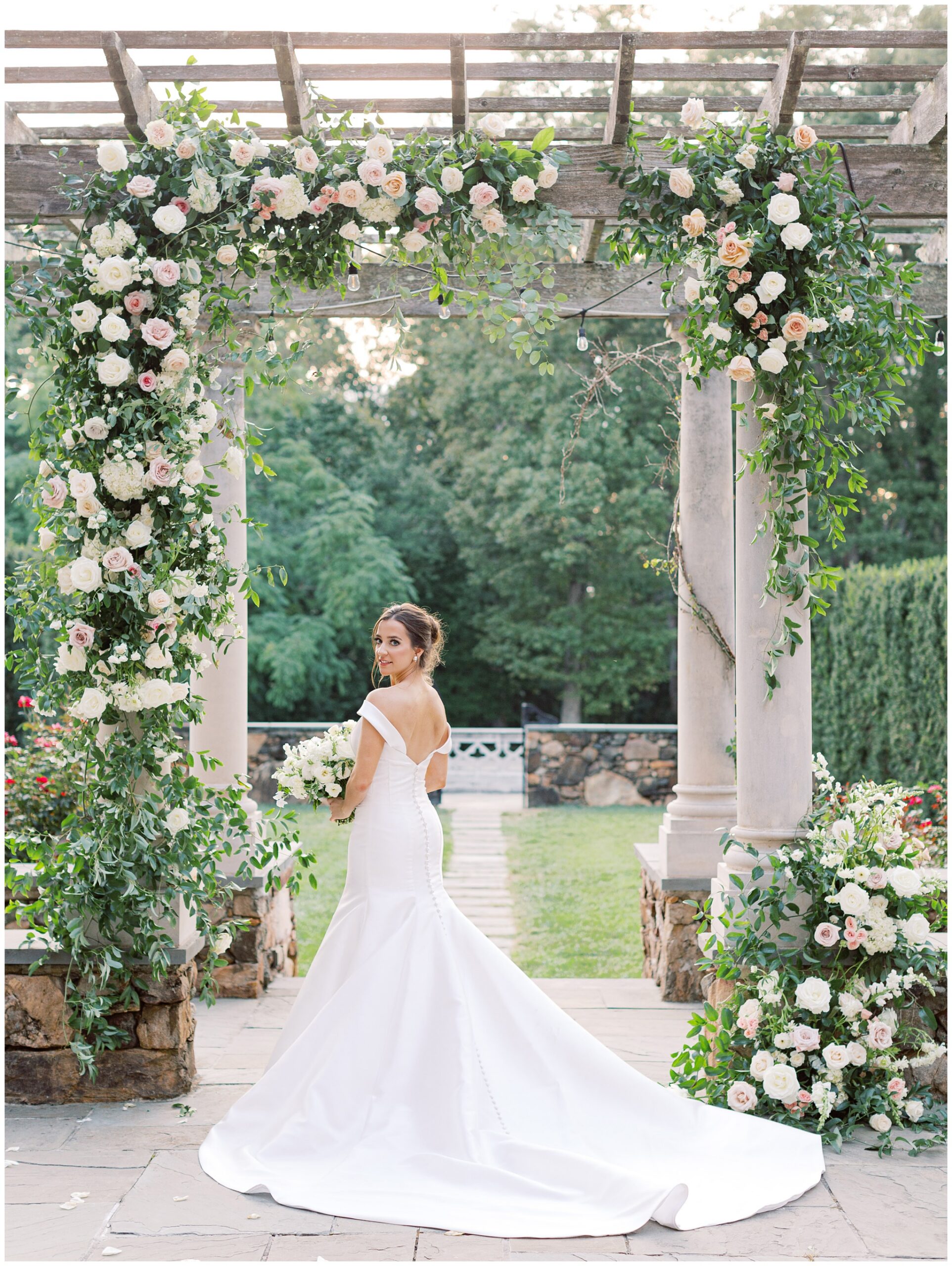 Bridal portrait of a bride beneath a lush floral arch on the Bluestone Terrace