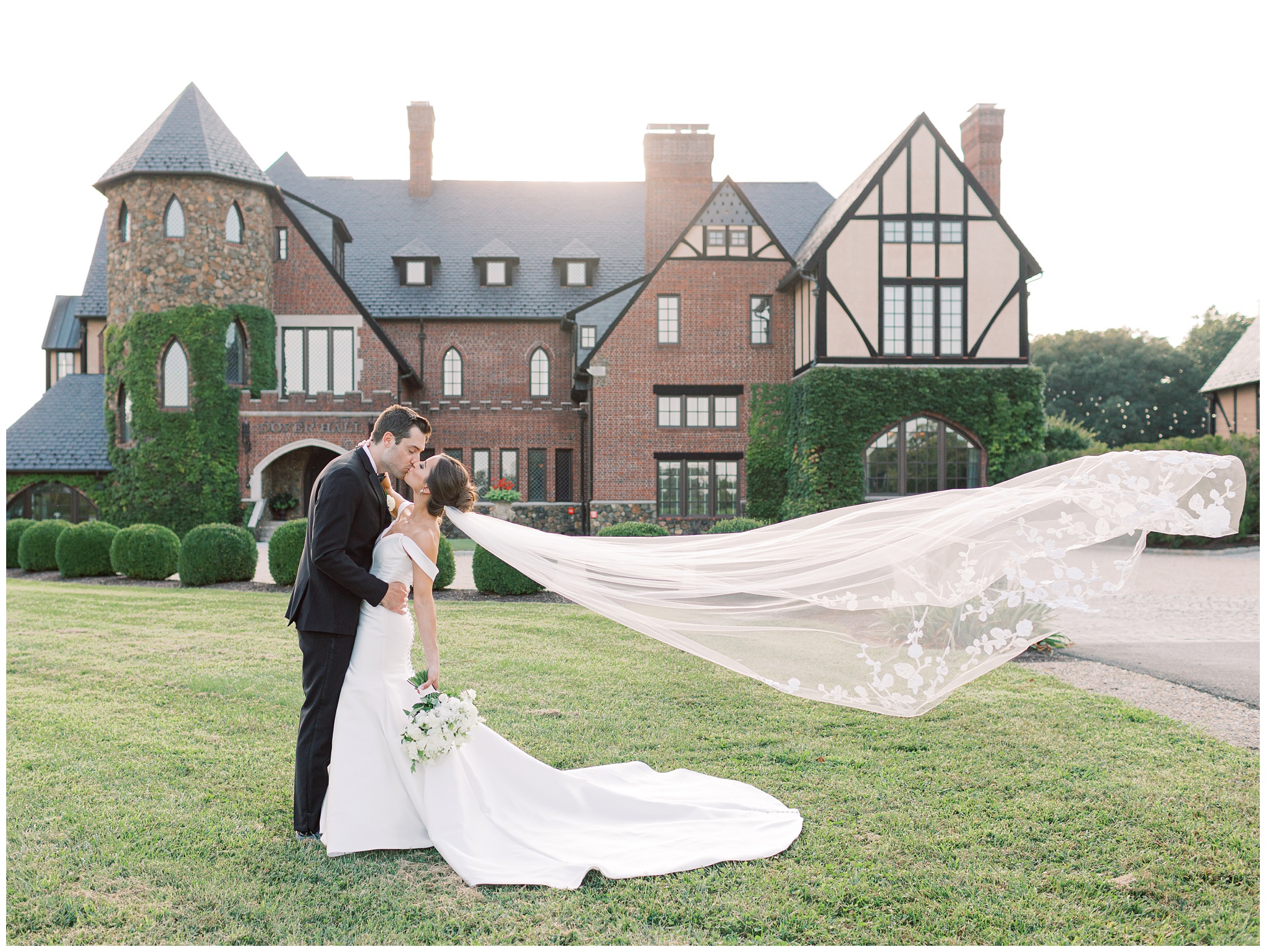 Bride and groom kissing outside Dover Hall with the bride’s veil blowing in the wind