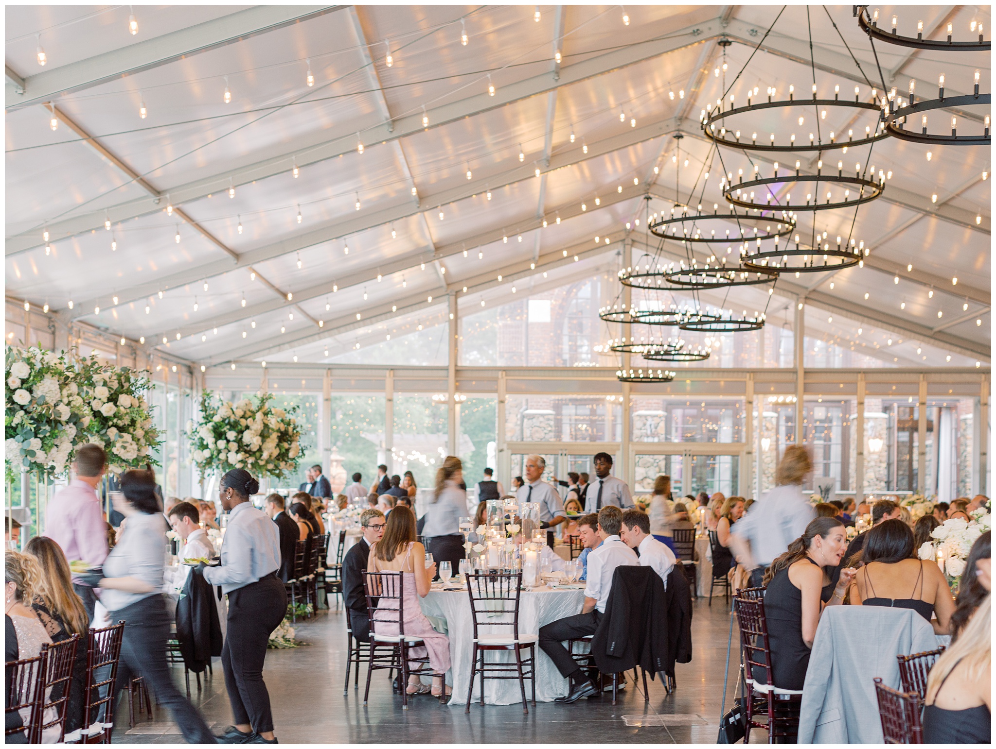 Wedding guests celebrating in the Glass Hall as servers provide food and drinks with motion blur