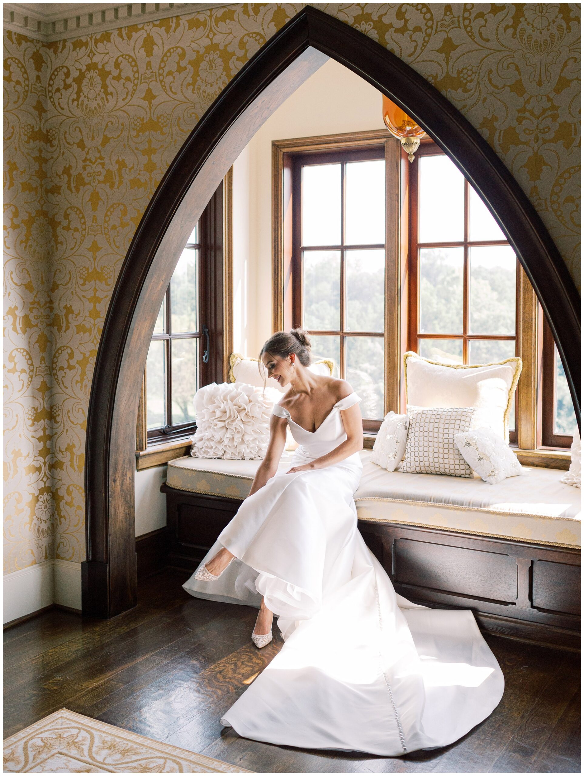 Bride putting on her shoes in the Queen Elizabeth Suite with soft light coming through the window