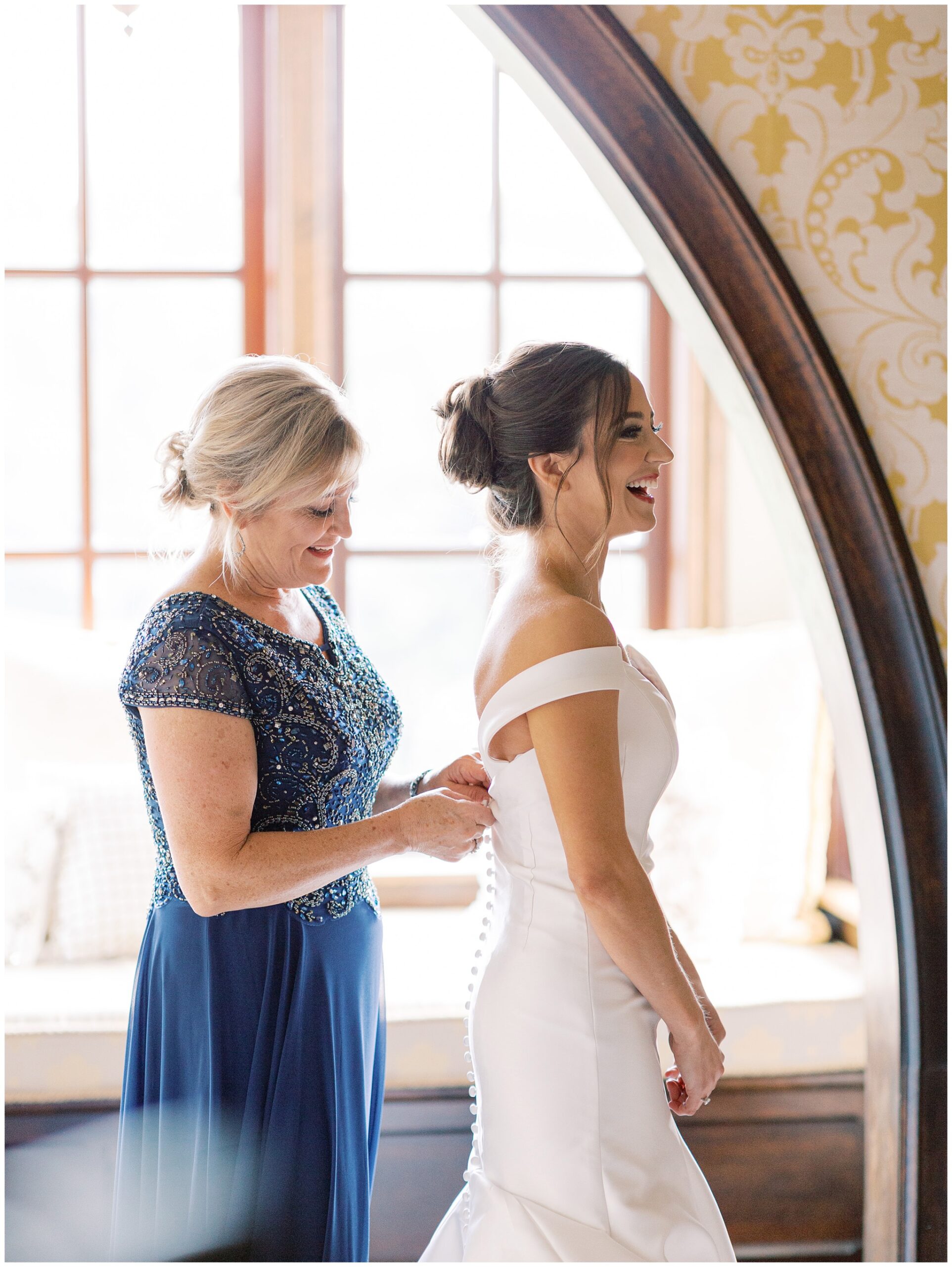 Mother of the bride helping the bride zip her wedding dress in the Queen Elizabeth Suite