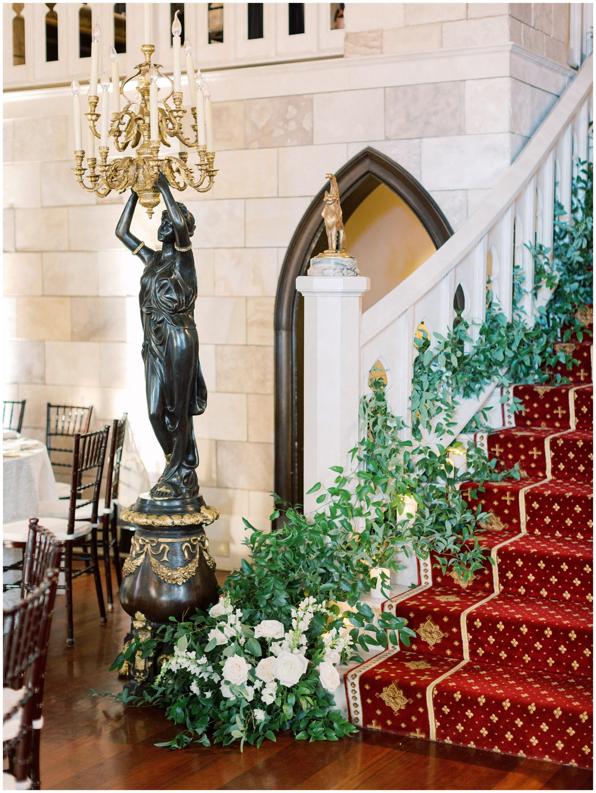 Ballroom reception with greenery and floral arrangements climbing the staircase