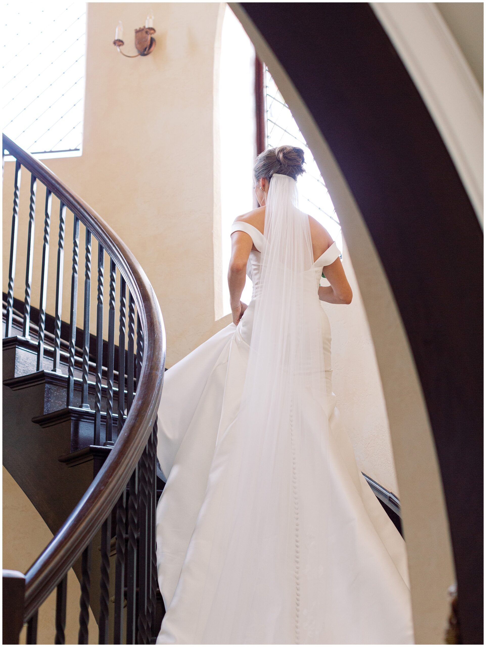 Bride walking up the ornate spiral staircase at Dover Hall during her wedding day