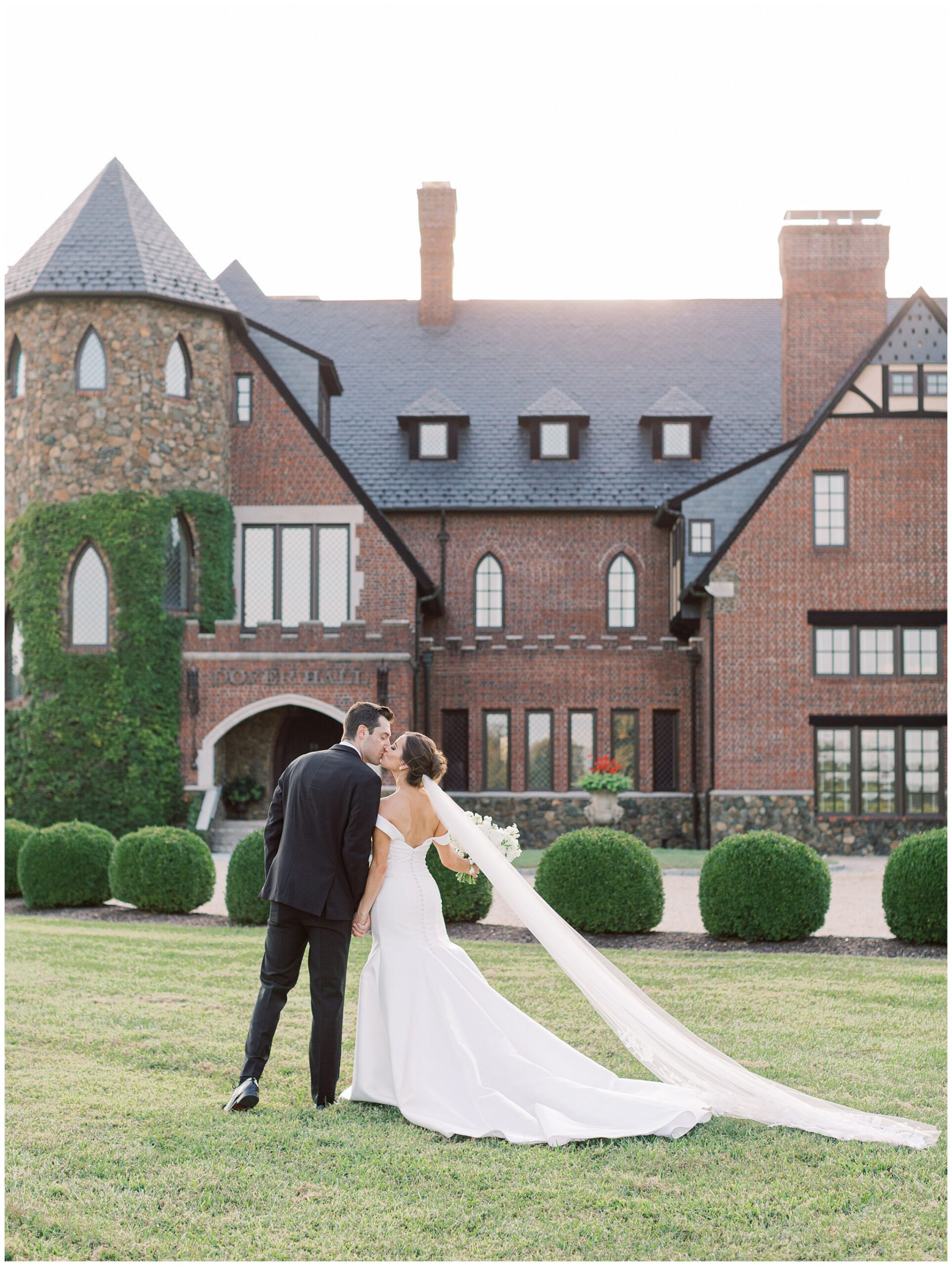 Bride and groom kissing in front of Dover Hall