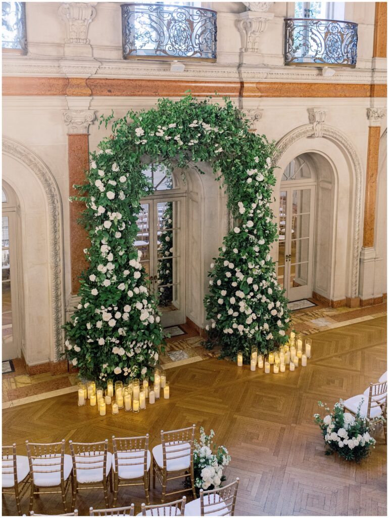 Ballroom ceremony with a floral arch framing the arched doorway
