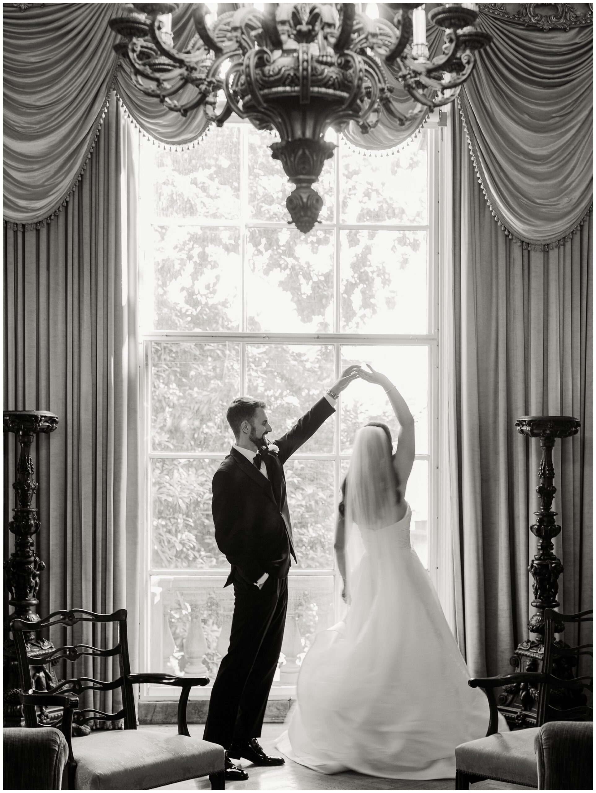 Groom kissing bride’s hand in the English Drawing Room at Larz Anderson House wedding