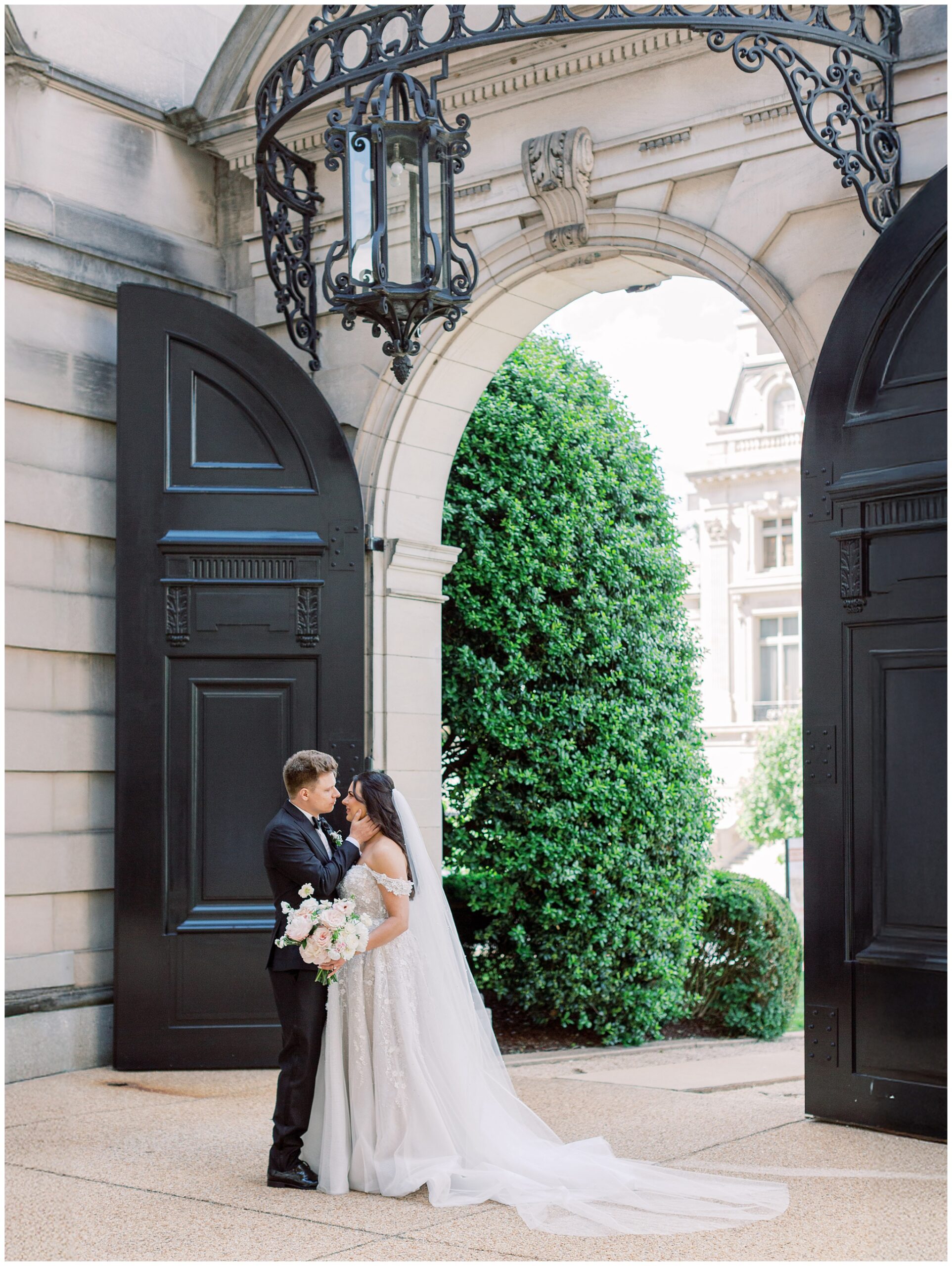 Newlywed couple standing against the grand black doors of Anderson House